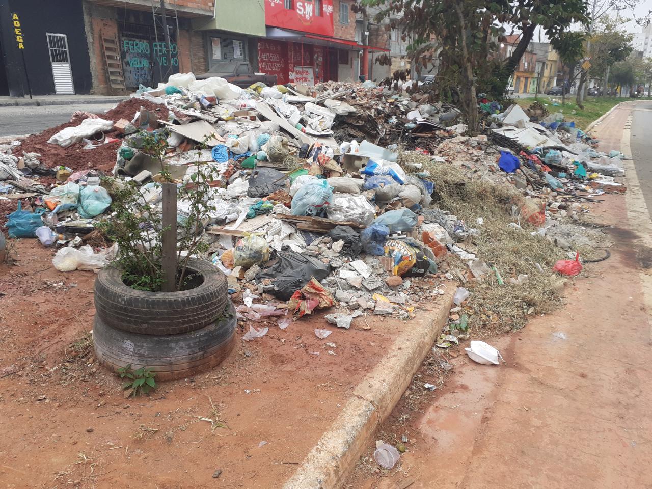 #PraTodosVerem foto do local antes da revitalização. Visualiza-se um amontoado de lixos e entulhos por toda a extensão do canteiro central.